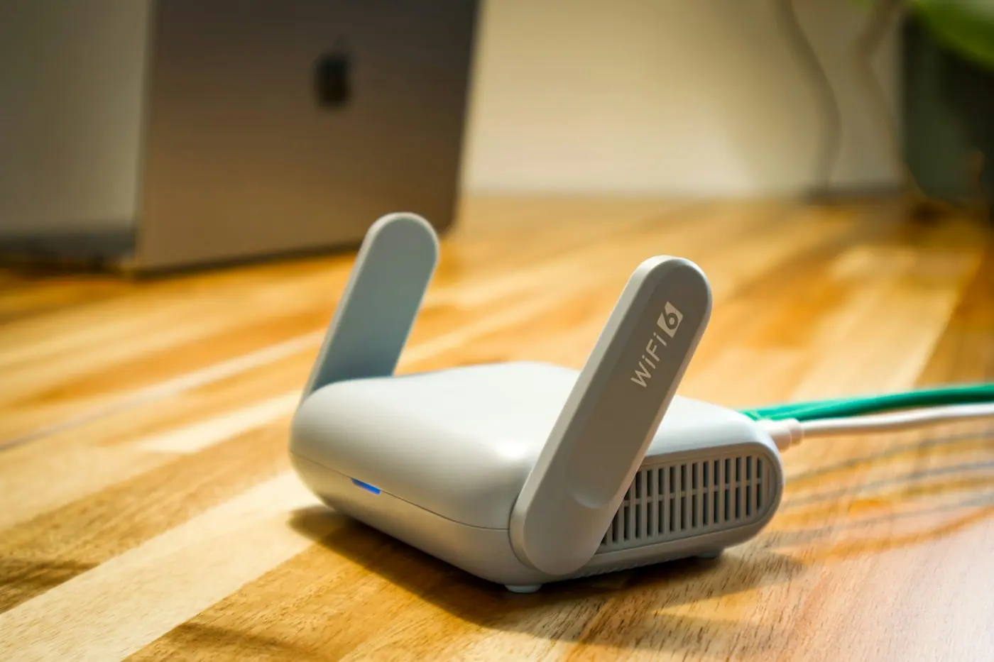 Router Wi-Fi compacto sobre una mesa de madera con un cable de red conectado
