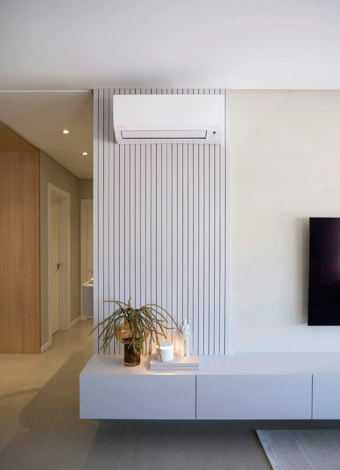 Mini split blanco montado sobre un panel de lambrín en una sala moderna
