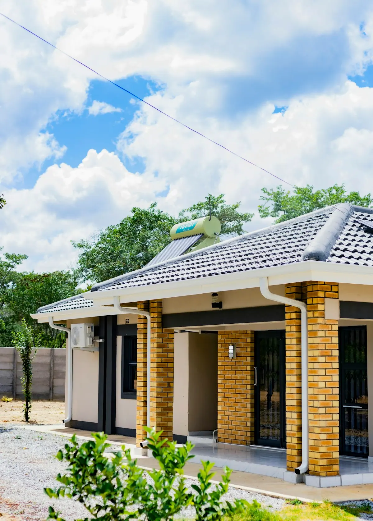 Casa de un nivel con calentador solar de agua en el techo y aire acondicionado en la fachada